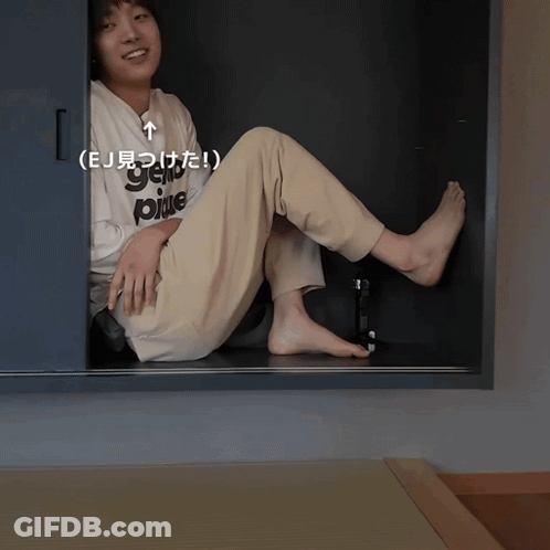Person Wearing 'EJ' Shirt Sitting In Closet GIF