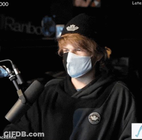 Person Wearing Mask And Beanie At Microphone GIF