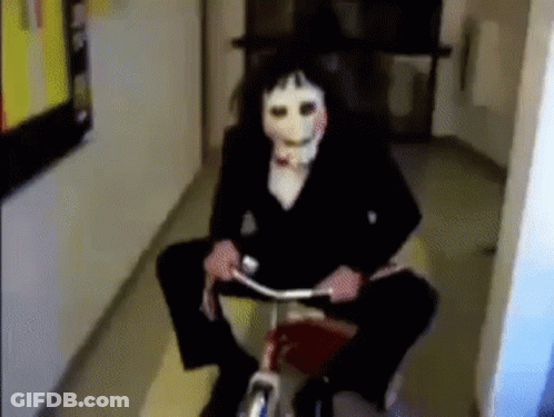 Person Wearing Puppet Mask Riding Bicycle In Hallway GIF
