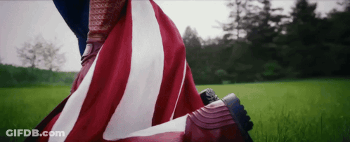 Person With American Flag Over Feet In Field GIF