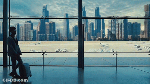 Person With Suitcase Looking Out Window At City GIF