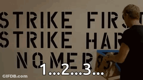 Person Working On Wall Saying Strike First Strike Hard No Mercy GIF