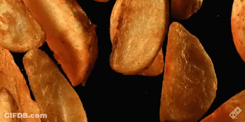 Pile Of Potato Wedges On Black Surface GIF
