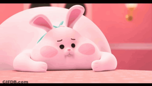 Pink Bunny With Bow Laying On Table GIF