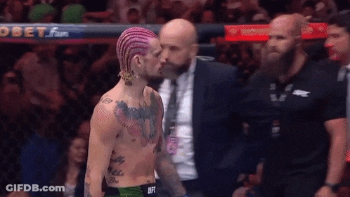 Pink Hair Man Talking To Suit Man At Obet Sign GIF