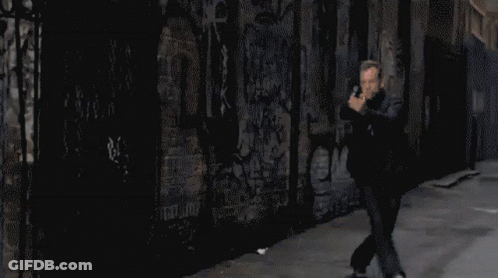 Pixelated Man Holding Gun In Front Of Graffiti Wall GIF