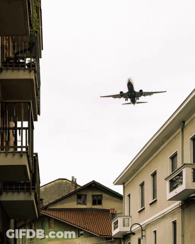 Plane Flying Over Building With Balcony GIF