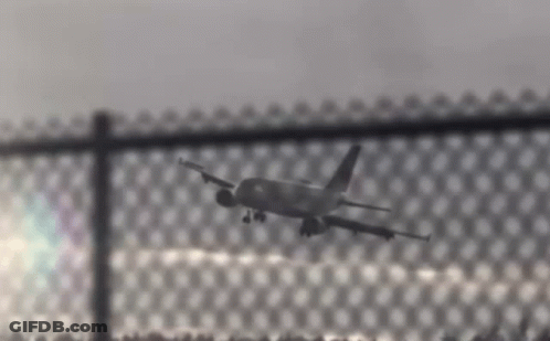Plane Flying Over Chain Link Fence GIF