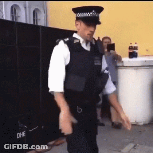 Police Officer Dancing In Front Of Yellow Building GIF