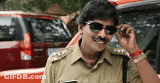 Police Officer In Sunglasses And Fake Mustache Smiling In Front Of Red Car GIF