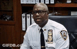 Police Officer With Glasses And Tie Sitting GIF