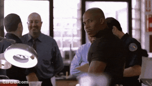 Police Officers Standing Around Table With Light GIF
