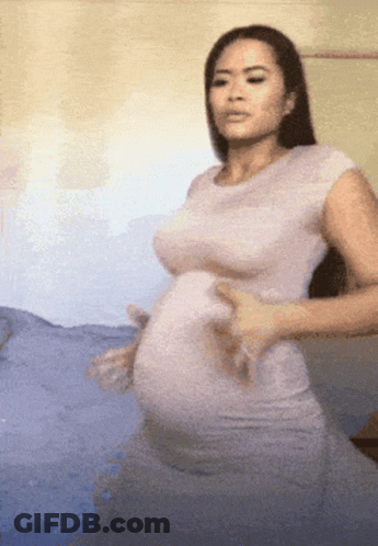 Pregnant Woman In White Dress On Bed GIF