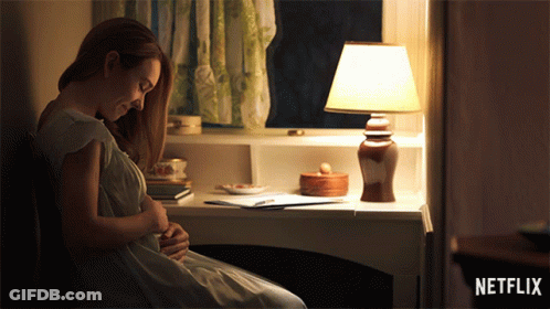 Pregnant Woman Sitting At Desk With Lamp And Netflix Logo GIF