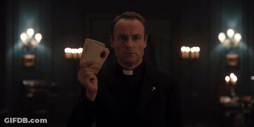 Priest Holding Paper With Cross On Jacket GIF