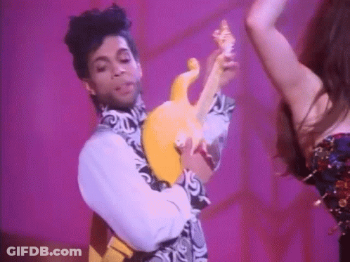Prince Is Holding A Yellow Guitar While Dancing With A Woman Behind Him . GIF