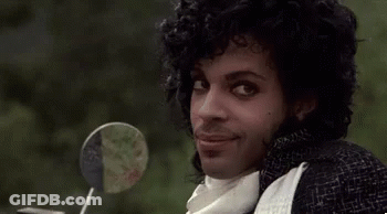 Prince Is Smiling While Sitting On A Motorcycle With A Lollipop In His Hand . GIF