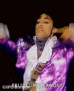 Prince Is Wearing A Purple Jacket And Tie And Is Dancing On Stage . GIF