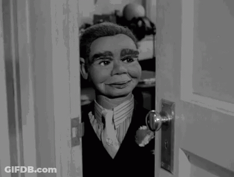 Puppet In Suit Looking Out Doorway GIF