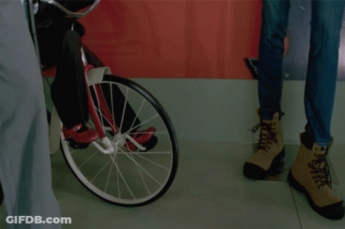 Puppet Riding Bike Next To Woman's Jeans GIF
