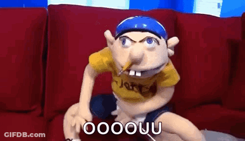 Puppet Sitting On Couch With Pencil In Mouth GIF