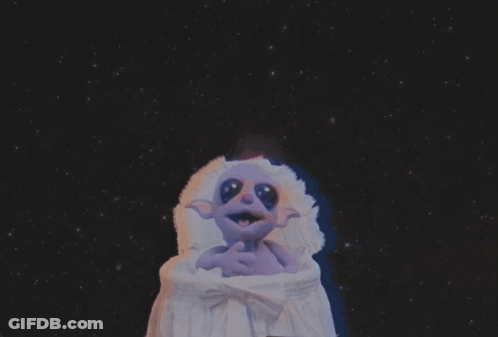 Purple Cartoon Character Sitting In Crib GIF