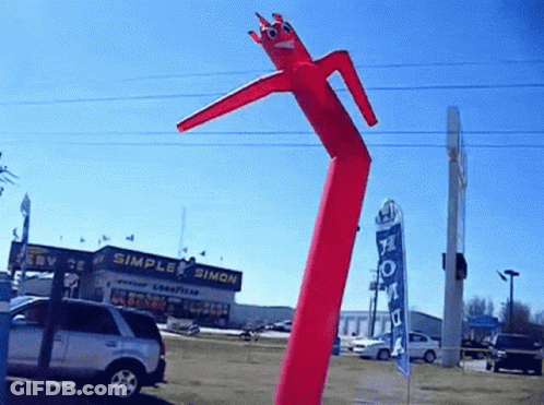 Red Air Dancer In Front Of Simple Simon Building GIF