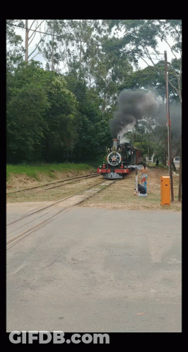 Red And Black Train Going Down Tracks With Smoke GIF