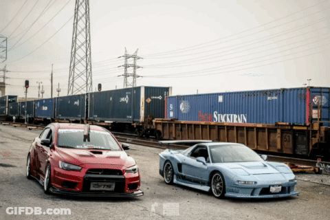 Red And Blue Cars In Front Of Stocktrain Container GIF