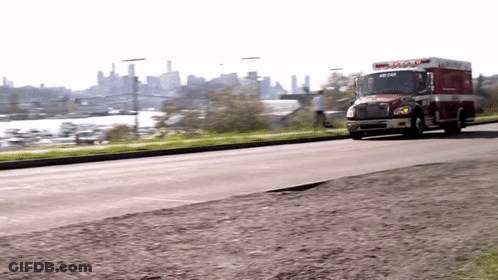 Red And White Ambulance Driving Down City Street GIF