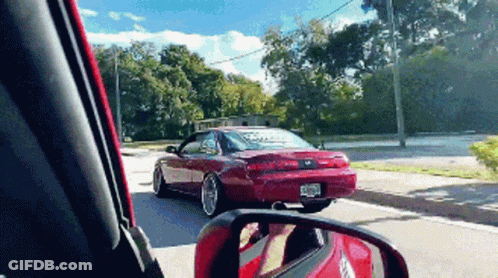 Red Car Driving Down Street With License Plate Saying Ecr GIF