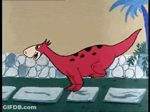 Red Dinosaur Standing Next To Stone Wall GIF
