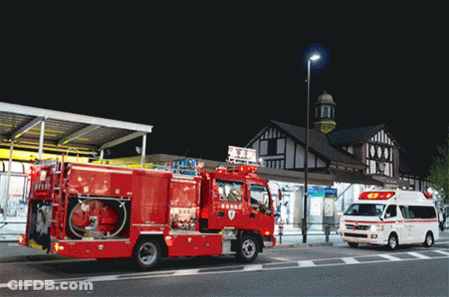 Red Fire Truck And Ambulance Parked In Front Of Building GIF
