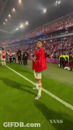 Red-Green Shirt Man Walking Soccer Field Crowd GIF