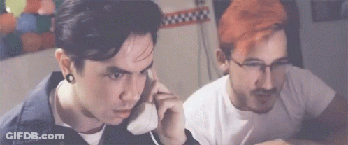 Red Hair Man Talking On Phone Next To Man With Glasses GIF