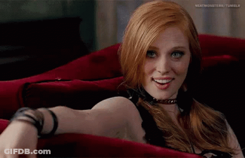 Red-Haired Blue-Eyed Woman On Red Couch GIF