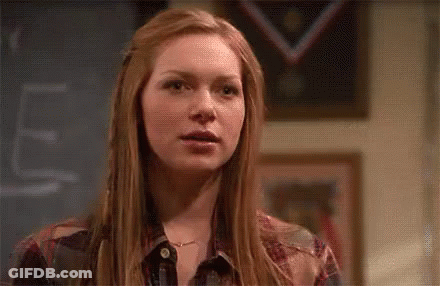 Red-Haired Woman At Chalkboard With Windblown Hair GIF