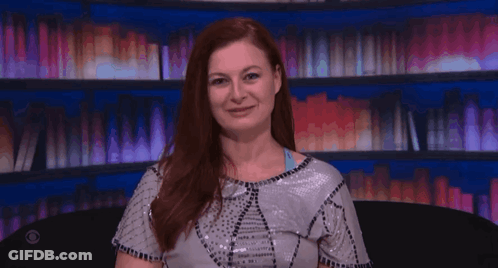 Red-Haired Woman Laughing In Front Of Bookshelf GIF
