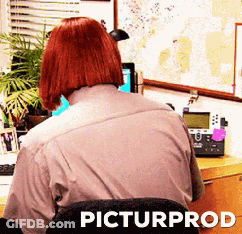 Red Haired Woman Sitting At Desk With Computer And Telephone GIF