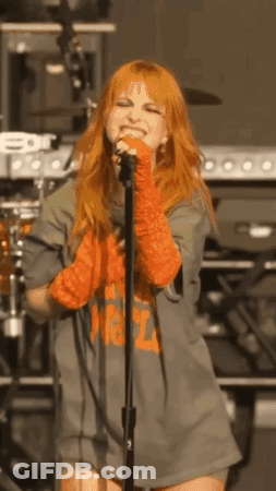 Red-Haired Woman Standing At Microphone On Stage GIF