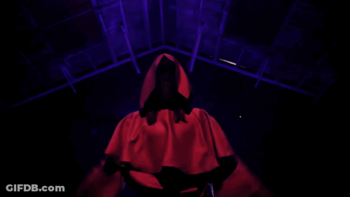 Red Hooded Person Arms Outstretched In Dark Room GIF