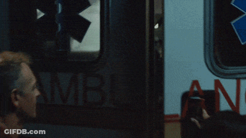 Red Shirt Man Holding Gun Beside Person In Wheelchair GIF