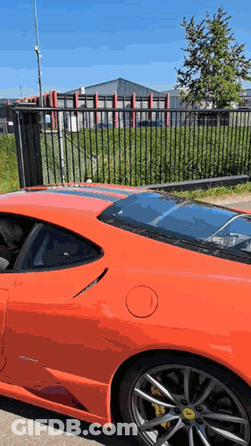 Red Sports Car Parked By Black Fence GIF