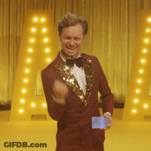 Red-Suited Bow-Tied Man Holding Card Near Large A GIF