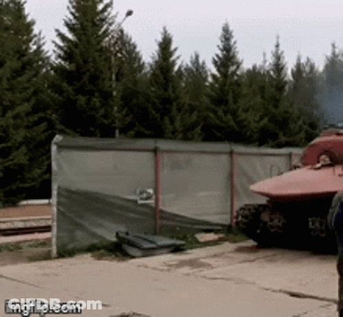 Red Tank Parked By Fence With Trees GIF