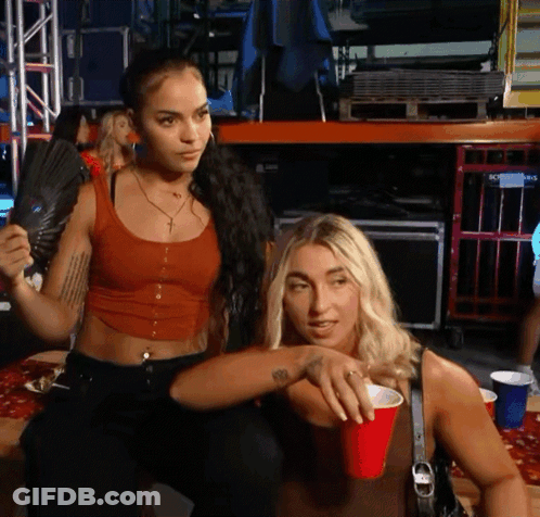 Red Tank Top Woman Holds Fan Near Blonde With Red Cup GIF