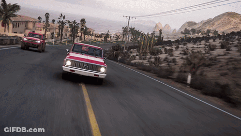 Red Truck Driving Down Desert Road With Mountains GIF