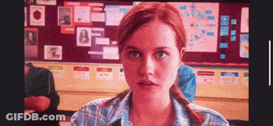 Redhead Woman Sitting In Front Of Bulletin Board GIF