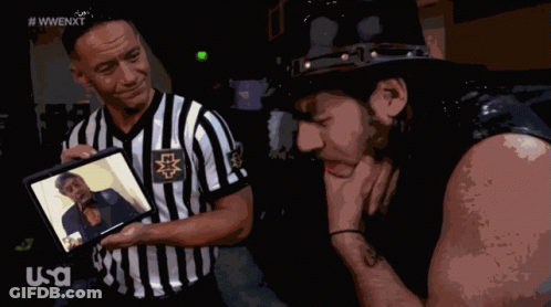 Referee Shows Wrestler Picture, Other Wrestler Looks Down GIF