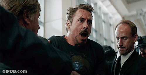 Robert Downey Jr. Is Being Held By A Group Of Men While Wearing A Black T-Shirt . GIF